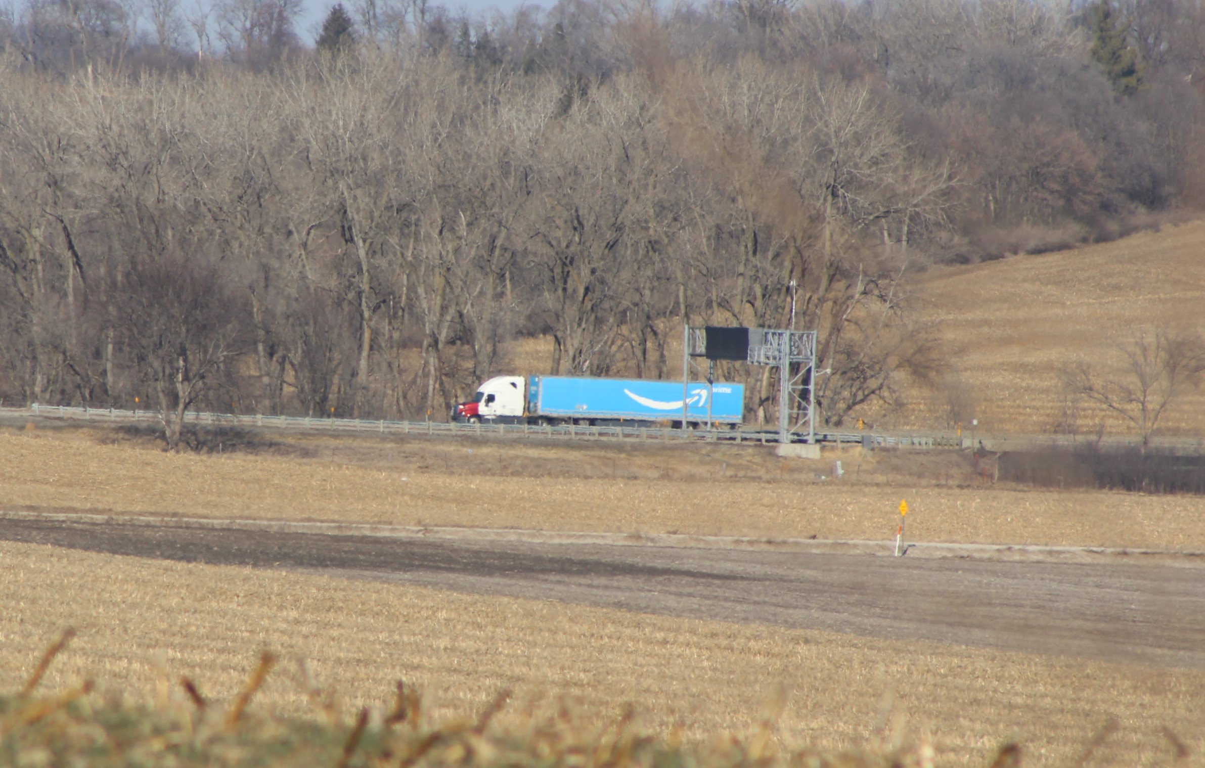 Interstate from the barn. A truck on I-80 sports the familiar Amazon Smile logo, seen from the hay mow of the barn on Owl Acres. A picture with reverse composition appears in the text.
